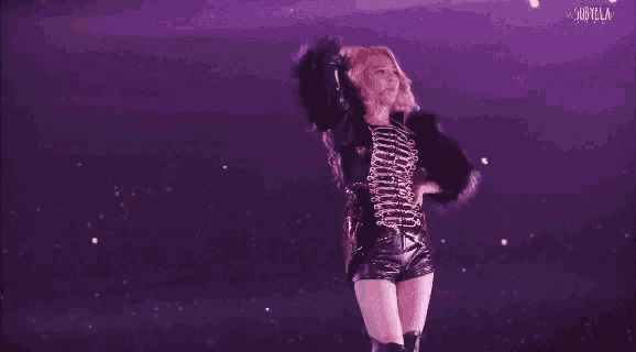 a woman in a fur coat is dancing on a stage in front of a crowd .