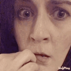 a close up of a woman 's face with a hand on her mouth .