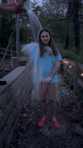a man in a blue shirt is being sprayed with water from a bucket