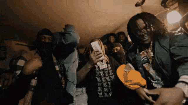 a group of men are dancing in a room with one wearing a louis vuitton sweatshirt
