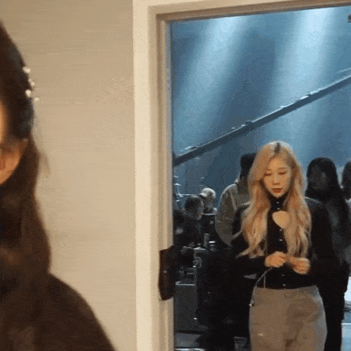 a woman is standing in a doorway looking at another woman
