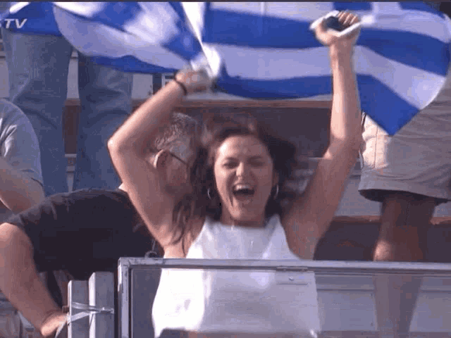 a woman holds a blue and white flag over her head in a crowd
