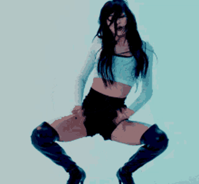 a woman in a white crop top and black shorts is kneeling down .