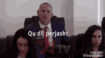 a man in a suit and tie is giving a speech in front of a group of women .