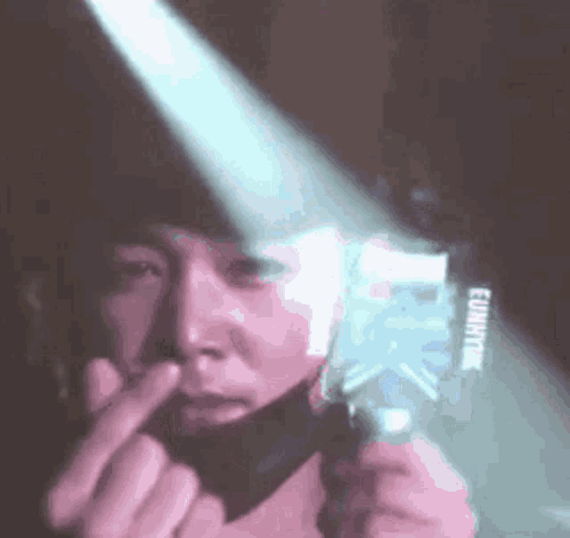 a person is holding a flashlight in front of their face and making a funny face .