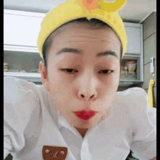 a woman wearing a yellow headband and red lipstick is making a face .