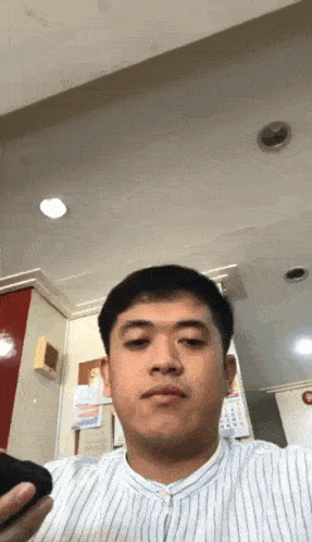 a man in a striped shirt holds a cell phone