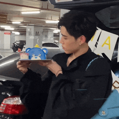 a man is holding a tray with a teddy bear on it in a parking garage