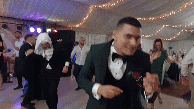 a man in a tuxedo is dancing in a room with people