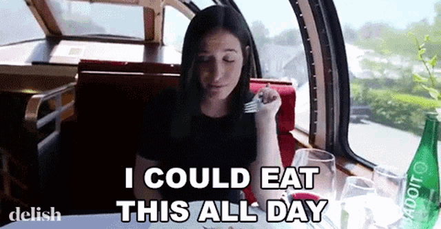 a woman is sitting at a table with a fork in her hand and the words i could eat this all day above her .
