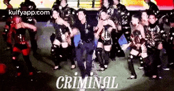 a group of people are dancing on a stage and the word criminal is on the bottom of the picture .