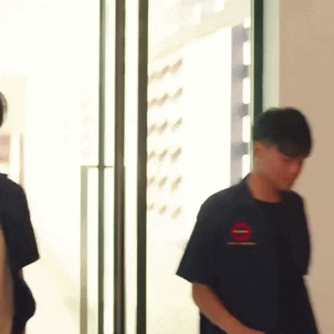 a man in a black t-shirt is walking through a doorway .