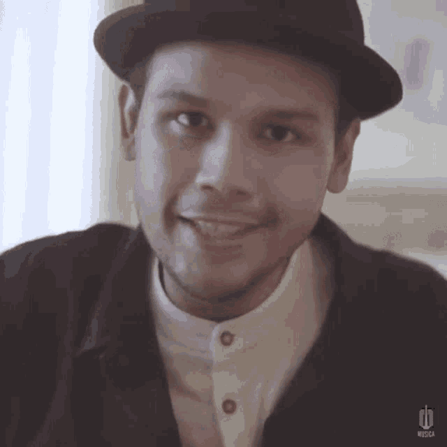 a close up of a man wearing a hat and a jacket with the word musica on it