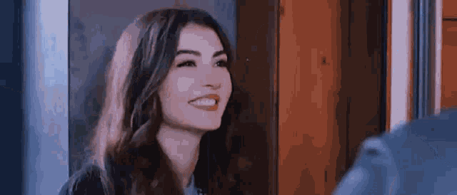 a woman is smiling and looking at the camera while standing in front of a mirror .