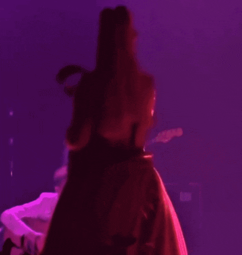 a woman in a red dress and hijab is holding a microphone on a stage .