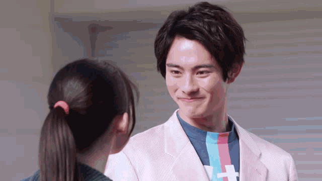 a man in a pink suit is talking to a woman in a ponytail