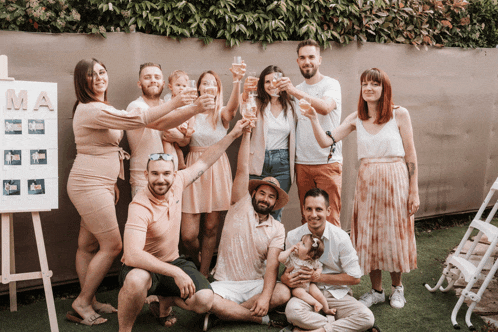 a group of people toasting with champagne in front of a sign that says " ma "