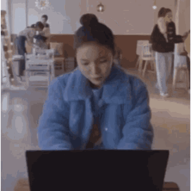 a woman is sitting at a table using a laptop computer .