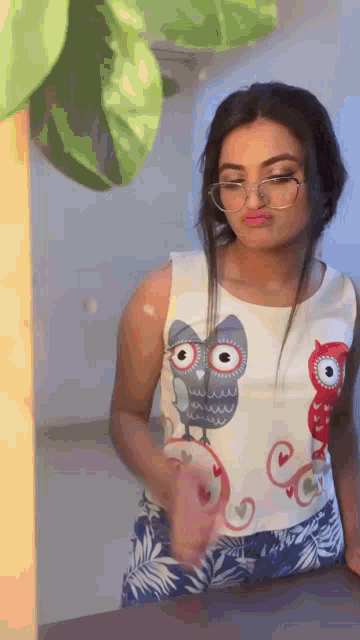 a woman wearing glasses and a white top with an owl on it