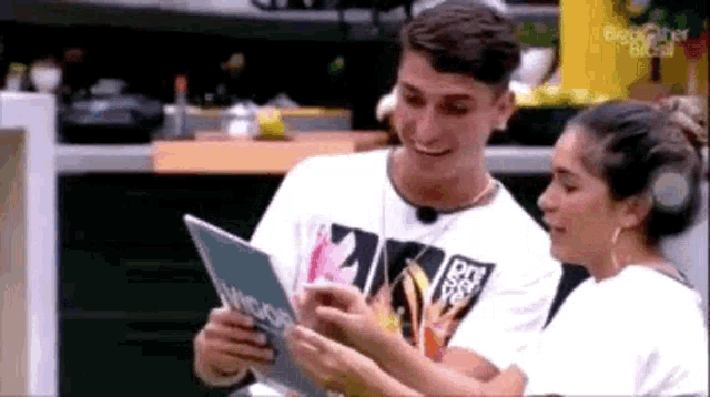 a man and a woman are sitting next to each other reading a book .