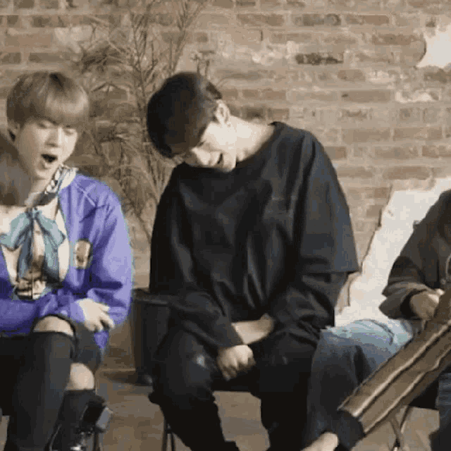 a group of people are sitting in chairs in front of a brick wall