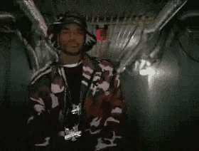 a man in a red and white jacket is standing in a dark room with wings on his back .
