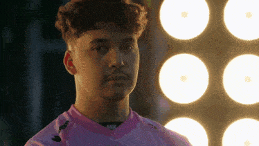 a young man wearing a pink shirt with the word kappa on the sleeve