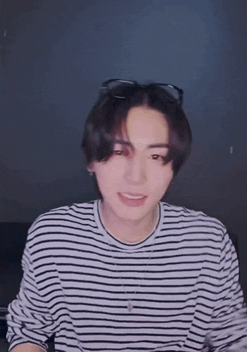 a young man wearing a black and white striped shirt and sunglasses is smiling .