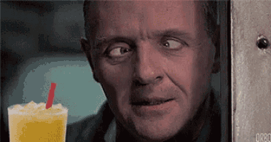 a man is looking at a drink with a red straw .