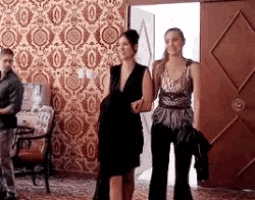 three women are standing in a room with a man standing behind them .