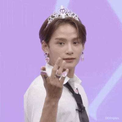 a man wearing a tiara and earrings is giving the middle finger .