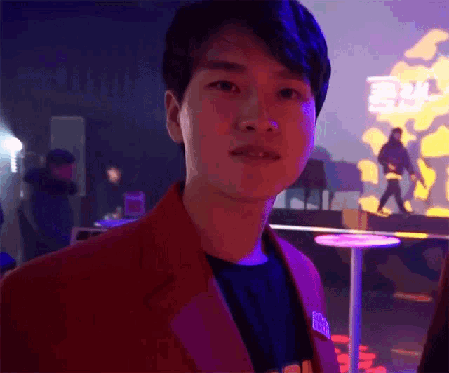 a man in a red jacket stands in front of a sign that says ' a '