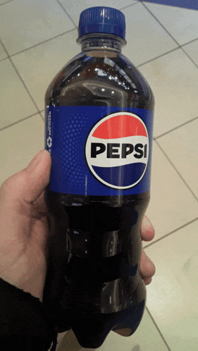 a person is holding a bottle of pepsi