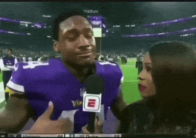 a man in a purple vikings jersey is being interviewed
