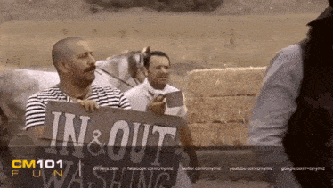 a man holding a sign that says in & out