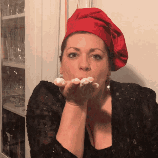 a woman wearing a red chef 's hat blowing a kiss