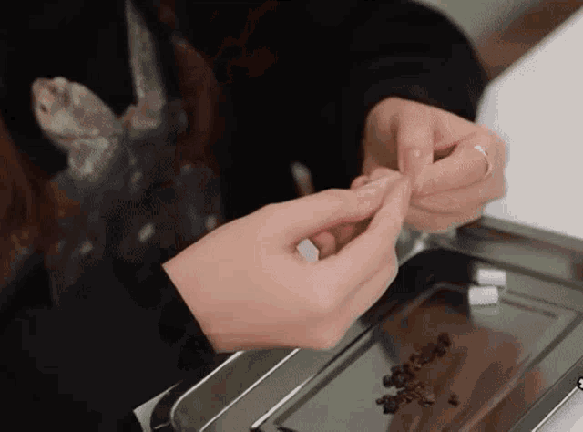 a close up of a person 's hands with a ring on a metal tray .