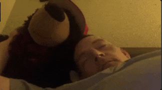 a man is sleeping in bed with a stuffed animal on his head .