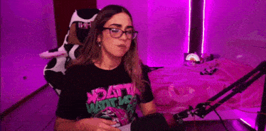 a woman in a cow costume is sitting in front of a microphone in a room with purple lights .