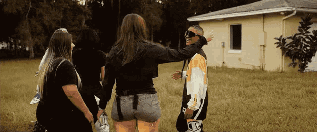 a group of people standing in front of a house with a man wearing a jacket that says ' a ' on it