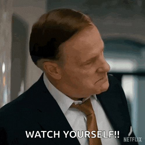 a man in a suit and tie is making a face and saying `` watch yourself '' .