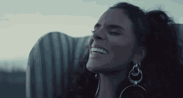a close up of a woman wearing earrings and a nose ring .