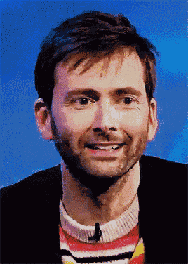 a man wearing a striped sweater and a black jacket smiles