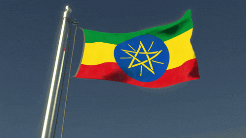 an ethiopian flag flies in the wind against a blue sky