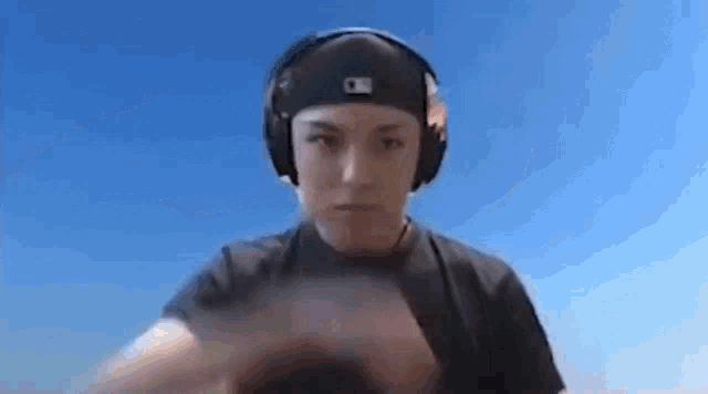 a man wearing headphones and a hat is making a face .