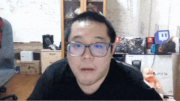 a man wearing glasses is sitting in front of a ps5 console