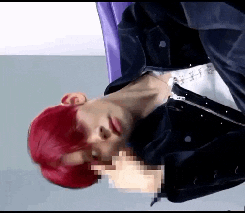 a man with red hair and a black jacket is laying on his back