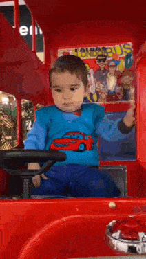 a little boy is sitting in a toy bus with a poster on the side that says sonic the hedgehog
