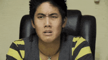 a man in a black and yellow striped shirt is sitting in a chair
