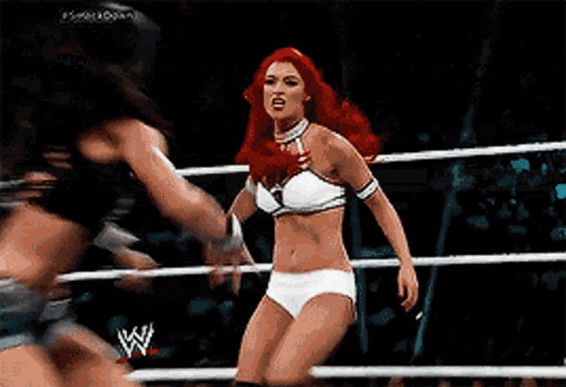 two women wrestling in a ring with a w logo on the ring